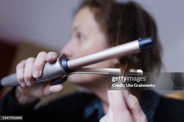 In this photo illustration a woman is curling her hair on December 08, 2023 in Bonn, Germany.