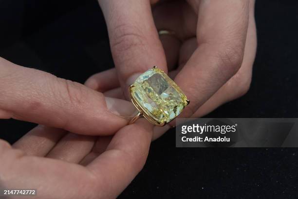Staff member holds important fancy vivid yellow diamond weighing 27.27 carats, estimate: $1 000-2 000 during a photocall at Phillips auction house...
