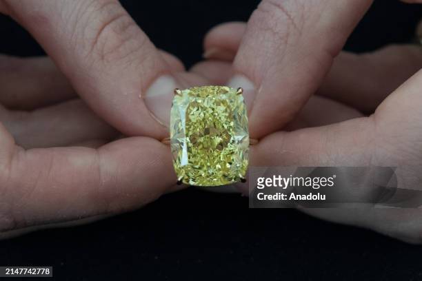 Staff member holds important fancy vivid yellow diamond weighing 27.27 carats, estimate: $1 000-2 000 during a photocall at Phillips auction house...