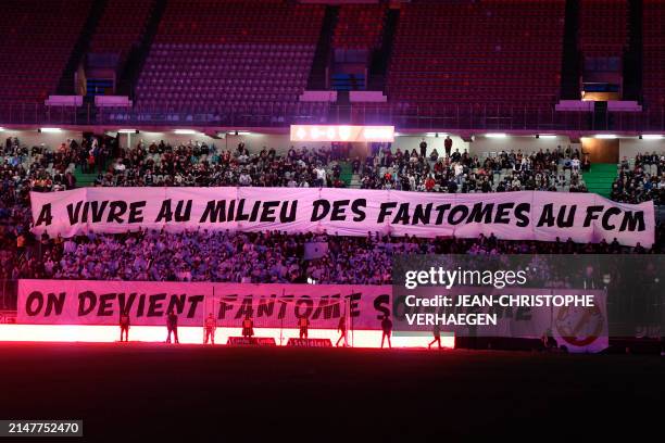 Metz supporters unvail banners which read "When you live with the ghosts of FC Metz, you become a ghost yourself" during the French L1 football match...