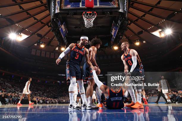 Josh Hart and Donte Divincenzo help up Jalen Brunson of the New York Knicks during the game against the Brooklyn Nets on April 12, 2024 at Madison...