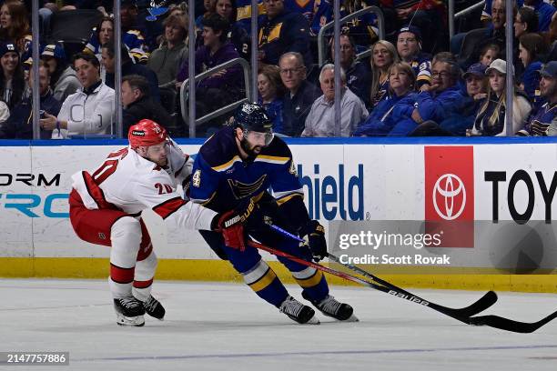 Nick Leddy of the St. Louis Blues controls the puck as Sebastian Aho of the Carolina Hurricanes pressures on April 12, 2024 at the Enterprise Center...