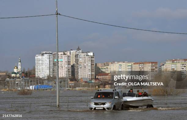 An SUV tows a boat in a flooded area in the city of Orenburg on April 13, 2024. Flooding in the Russian city of Orenburg became "critical" on April...