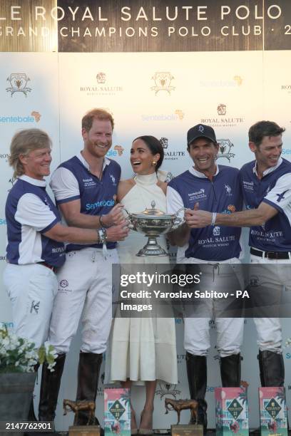 The Duchess of Sussex presents the trophy to her husband, the Duke of Sussex after his team the Royal Salute Sentebale Team defeated the Grand...