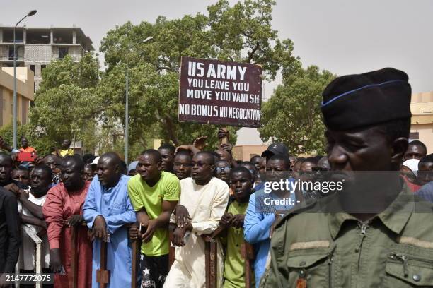 Protesters gather as a man holds up a sign demanding that soldiers from the United States Army leave Niger without negotiation during a demonstration...