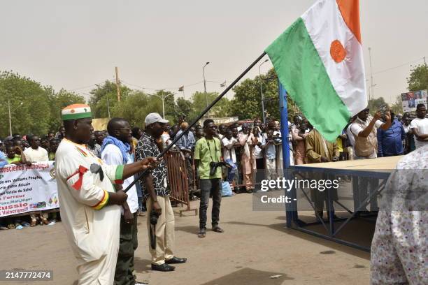 Man holds a flag of Niger as protesters gather during a demonstration for the immediate departure of United States Army soldiers deployed in northern...