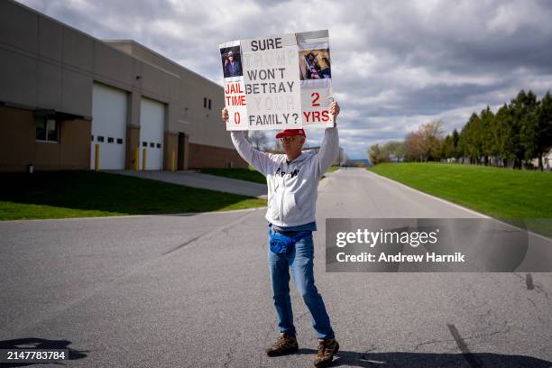 Man holds a sign that reads "Sure Trump Won't Betray Your Family?" as supporters wait in line for a rally for former U.S. President Donald Trump...