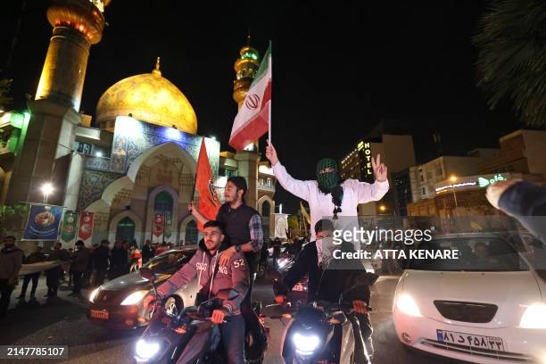 Demonstrators wave Iran's flag and Palestinian flags as they gather at Palestine Square in Tehran on April 14 after Iran launched a drone and missile...