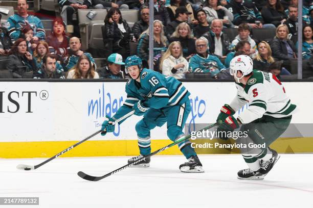 Jack Studnicka of the San Jose Sharks with the puck in front of Jake Middleton of the Minnesota Wild during the first period of a game at SAP Center...