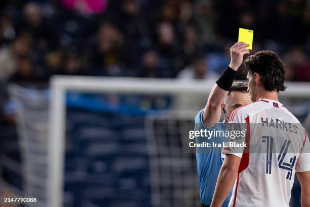 Ian Harkes of New England Revolution receives a yellow card after the referee reviews the VAR and decides to downgrade the offense from Red to Yellow...