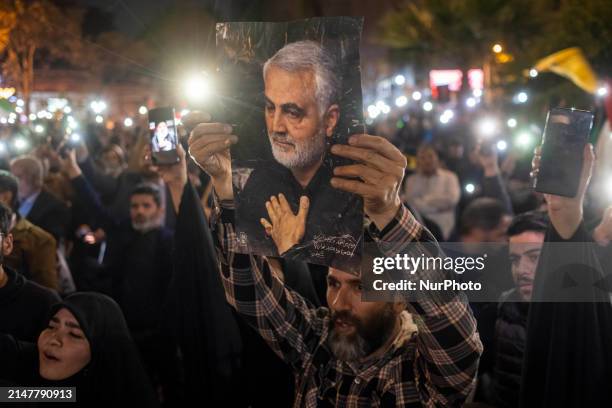 An Iranian man is holding up a portrait of the former commander of the Islamic Revolutionary Guard Corps' Quds Force, Major General Qassem Soleimani,...