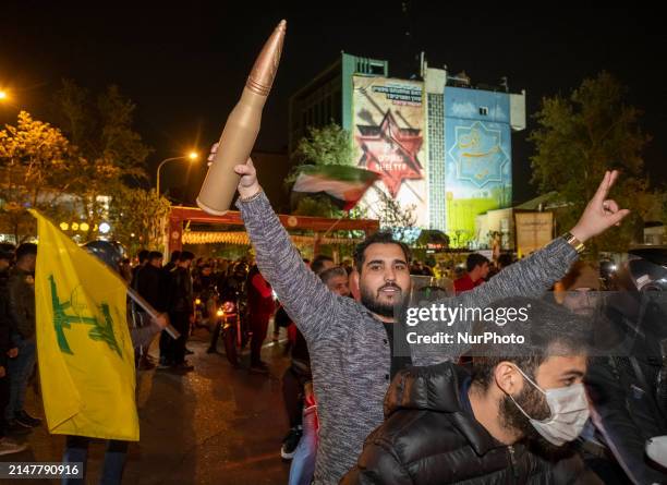 An Iranian man is holding a scale model of a cannon shell during a celebration in support of Iran's IRGC UAV and missile attack against Israel, in...