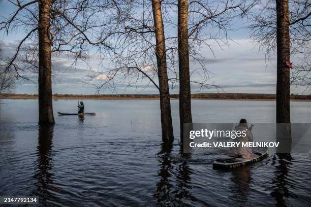 People sail on paddleboards in floodwater from the overflowing Nerl River outside the settlement of Bogolyubovo in the Vladimir region on April 13,...