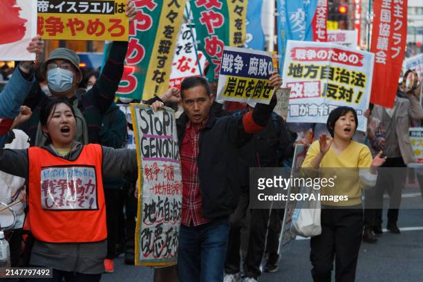 People carry signs calling for Palestinian rights as several hundred people take part in an anti-war protest in the streets of Shinjuku. The protest...
