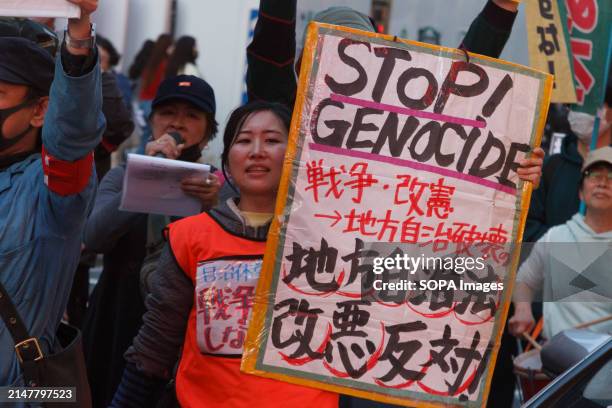 Japanese woman carries a sign calling for Palestinian rights as several hundred people take part in an anti-war protest in the streets of Shinjuku....