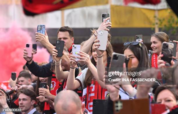 Fans of Bayer Leverkusen hold up their mobile phones as the bus carrying the players arrives ahead the German first division Bundesliga football...