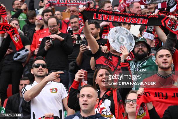 One Leverkusen fan displays a mock-up of the Bundesliga trophy as they cheer prior to the German first division Bundesliga football match Bayer 04...