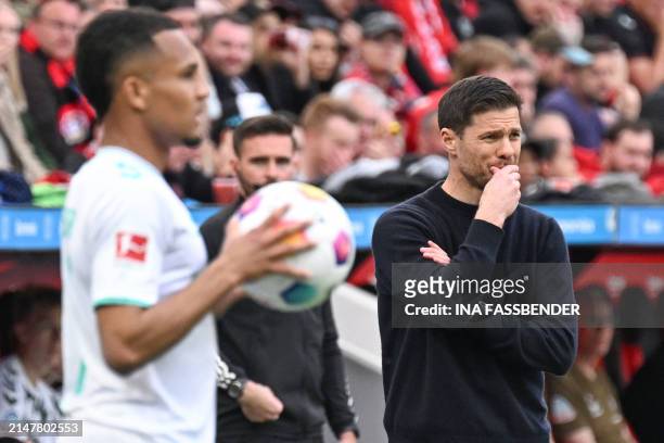 Bayer Leverkusen's Spanish head coach Xabi Alonso follows the action from the sidelines as a Bremen player waits to take a throw-in during the German...