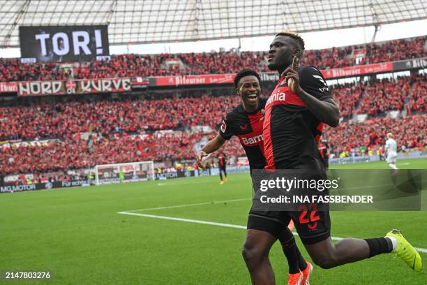 Bayer Leverkusen's Nigerian forward Victor Boniface celebrates scoring the opening goal from the penaty spot with his teammates during the German...