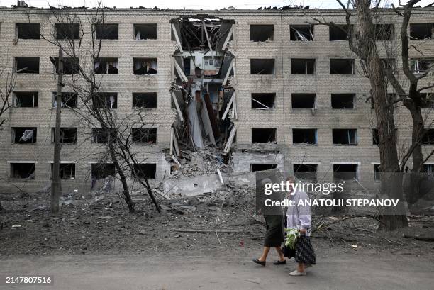 Elderly women walk past a hostel destroyed during a missile attack in the town of Selydove, Donetsk region, on April 14 amid the Russian invassion in...