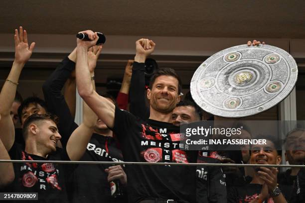 Bayer Leverkusen's Spanish head coach Xabi Alonso celebrates with a mock-up of the Bundesliga trophy with his players after the German first division...