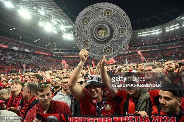 Bayer Leverkusen's fans celebrates with a mock-up of the Bundesliga trophy after the German first division Bundesliga football match Bayer 04...
