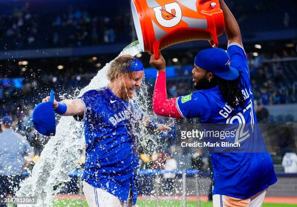 Justin Turner of the Toronto Blue Jays gets dunked with water by teammate Vladimir Guerrero Jr. #27 after their team defeated the Colorado Rockies in...