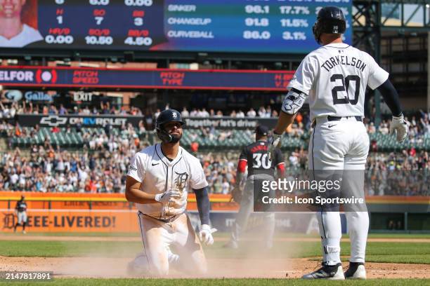 Detroit Tigers left fielder Riley Greene looks up at Detroit Tigers first baseman Spencer Torkelson after sliding into home plate to score a run...