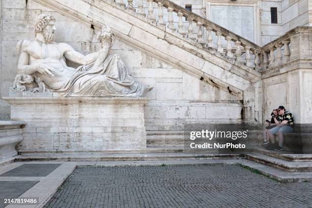 Couple is sitting on the steps next to the statue representing the river god Tevere in Rome, Italy, on April 14, 2024. Featuring 25,000...