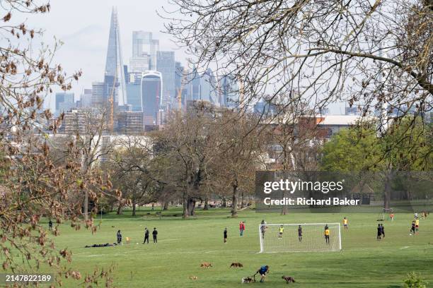 With the skyscrapers of the City of London, tha capital's financial district in the far distance, junior youth teams play a game of football on a...