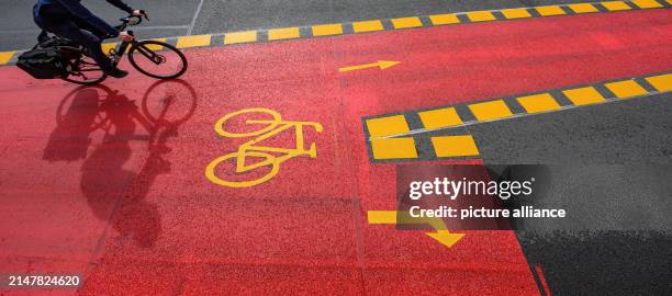 April 2024, Saxony, Dresden: A cyclist rides on a marked cycle path at Schillerplatz on the Blaues Wunder bridge over the Elbe. The cycle lane is...