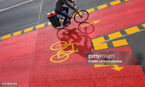 April 2024, Saxony, Dresden: A cyclist rides on a marked cycle path at Schillerplatz on the Blaues Wunder bridge over the Elbe. The cycle lane is...
