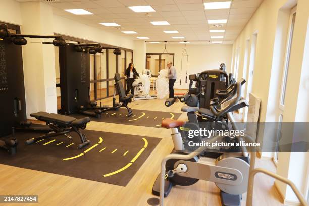 April 2024, Thuringia, Eisenberg: Employees remove the last covers from therapeutic sports equipment at the opening of a new orthopaedic...