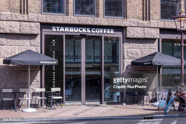Store of Starbucks Coffee shop chain located in Amsterdam city center with people sitting inside, enjoying a coffee after shopping in the cafe, while...