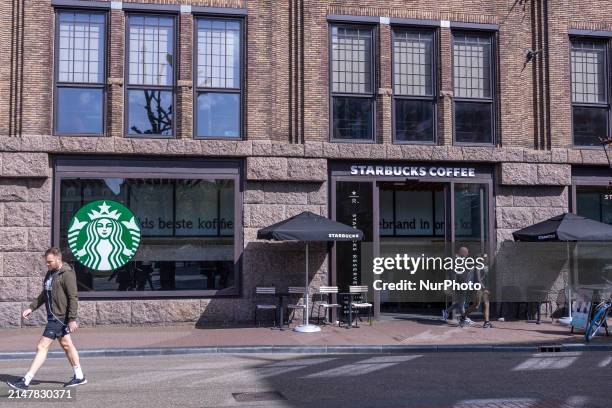 Store of Starbucks Coffee shop chain located in Amsterdam city center with people sitting inside, enjoying a coffee after shopping in the cafe, while...