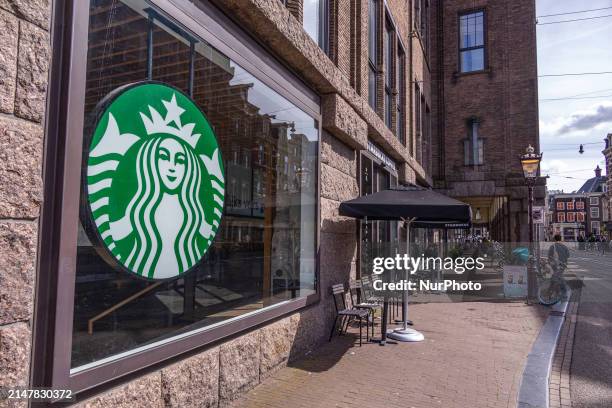 Store of Starbucks Coffee shop chain located in Amsterdam city center with people sitting inside, enjoying a coffee after shopping in the cafe, while...