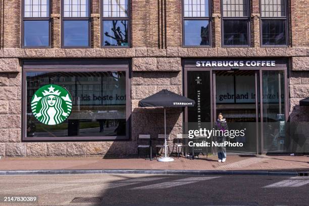 Store of Starbucks Coffee shop chain located in Amsterdam city center with people sitting inside, enjoying a coffee after shopping in the cafe, while...