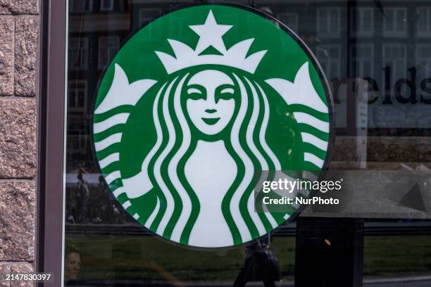 Store of Starbucks Coffee shop chain located in Amsterdam city center with people sitting inside, enjoying a coffee after shopping in the cafe, while...