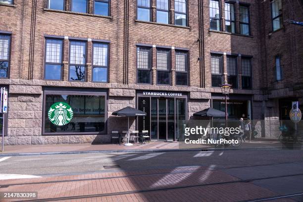 Store of Starbucks Coffee shop chain located in Amsterdam city center with people sitting inside, enjoying a coffee after shopping in the cafe, while...
