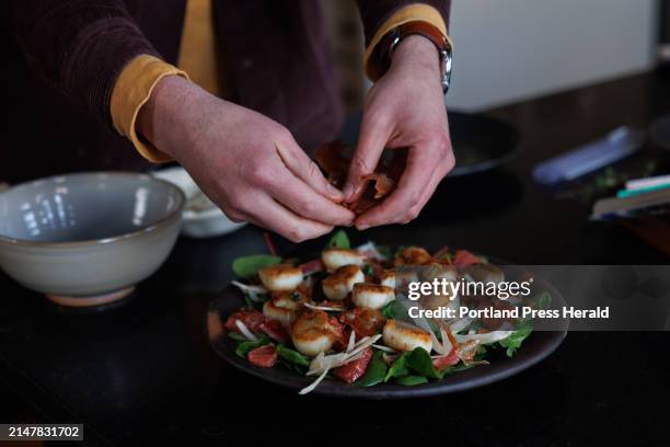 Ben Conniff, co-founder of Luke's Lobster, crumbles prosciutto over the scallops at his home in Portland on Thursday, January 4, 2024. The dish,...