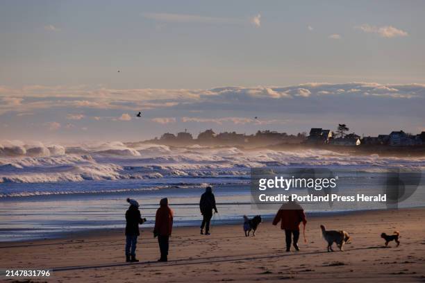 People walk along Fortunes Rocks Beach as large waves from the storm break in the distance on Wednesday, January 10, 2024.