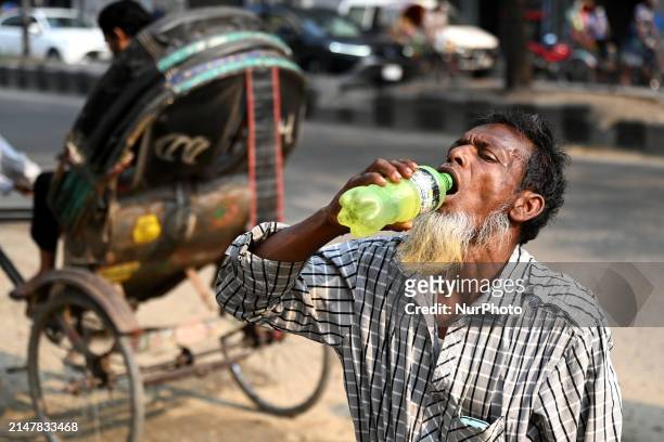 Rickshaw driver is drinking water from a roadside water pipeline on a day of high temperatures in Dhaka, Bangladesh, on April 15, 2024.
