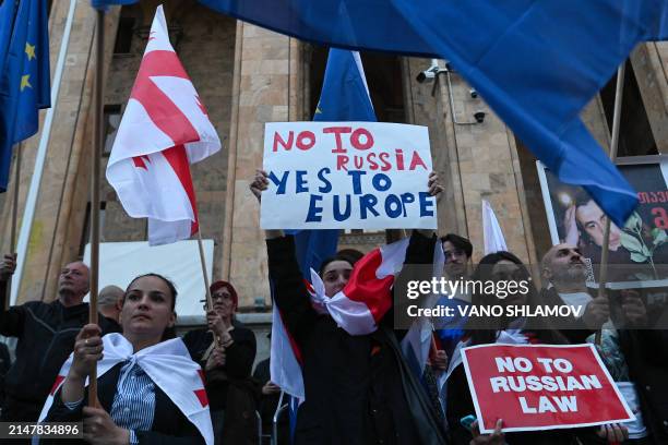 Georgian pro-democracy groups activists hold placards and wave flags of Georgia and flags of Europe as they protest against a repressive "foreign...