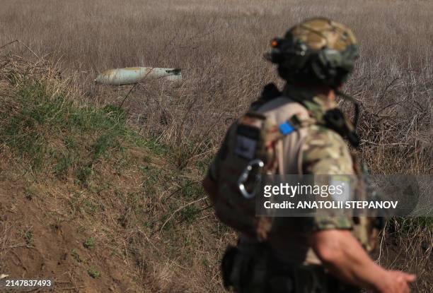 Soldier walks past an unexploded Russian FAB-500 aerial bomb in a field near the village of Ocheretyne not far from Avdiivka town in the Donetsk...