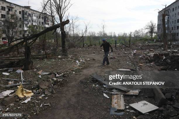 Local resident walks past apartment buildings destroyed by artillery in the village of Ocheretyne, near the town of Avdiivka, in the Donetsk region,...