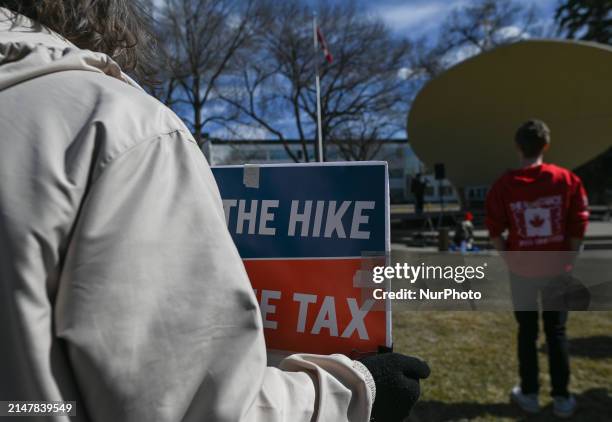 An activist holds 'Axe The Taxe' placard as local activists join a nationwide protest at the Alberta Legislative grounds opposing the proposed World...