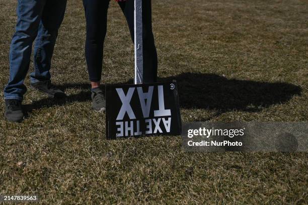 Activists hold 'Axe The Taxe' placard as they join a nationwide protest at the Alberta Legislative grounds opposing the proposed World Health...