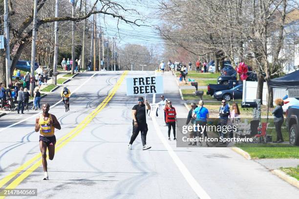 Sisay Lemma of Ethiopia runs as the lead runner while a spectator holds a sign "Free Beer" during the men's division of the 128th Boston Marathon on...