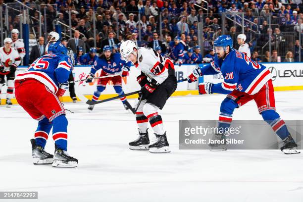 Parker Kelly of the Ottawa Senators skates with the puck against Chris Kreider and Ryan Lindgren of the New York Rangers at Madison Square Garden on...