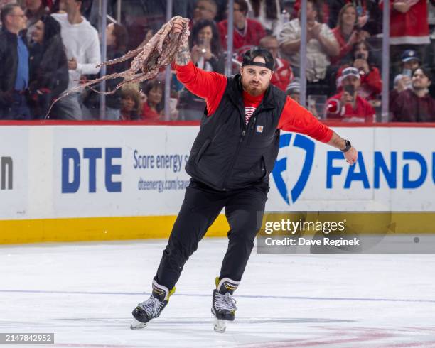 Member of the Detroit Red Wings ice crew scoops up an octopus during the third period of the game against the Montreal Canadiens at Little Caesars...